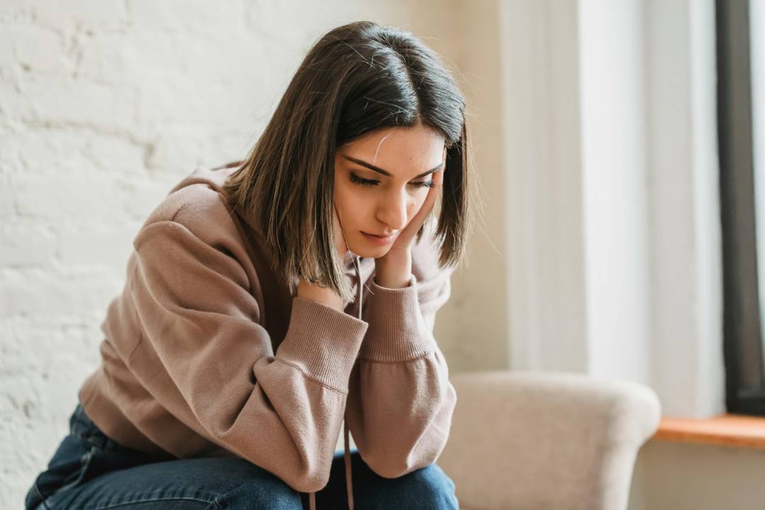 Jeune femme préoccupée, les mains sur les oreilles, évoquant l’inconfort lié aux acouphènes
