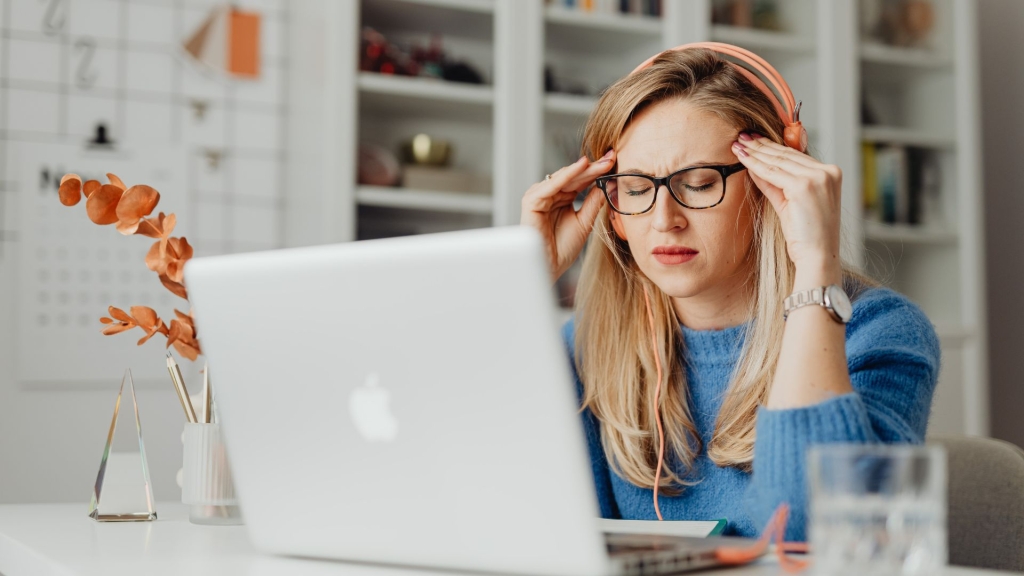Femme au travail ressentant une fatigue auditive en open space après une écoute prolongée au casque