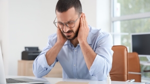 Homme ressentant une douleur à l’oreille liée à une fatigue auditive ou un stress auditif au travail