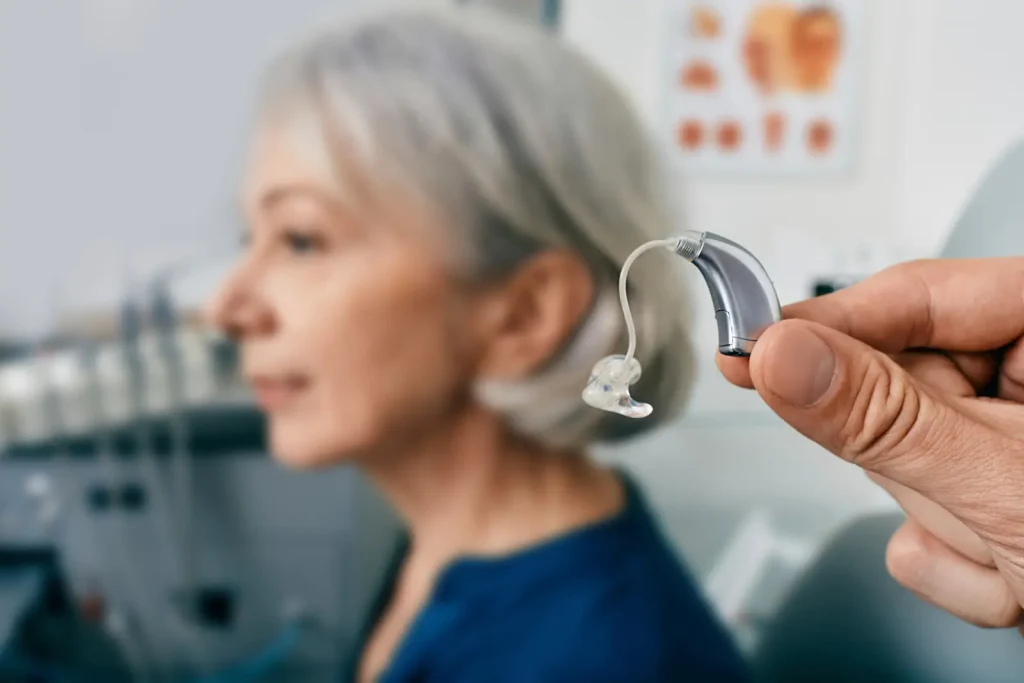 Contour d’oreille présenté devant une patiente senior lors d’un essai d’appareil auditif.